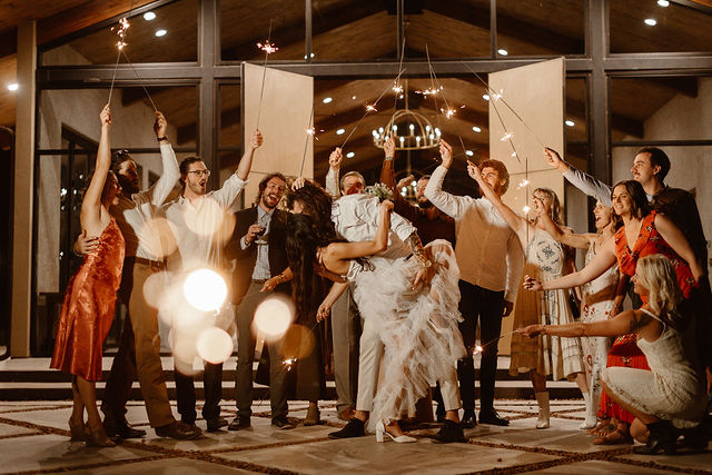 a couple wearing wedding attire kissing surrounded by friends and family holding sparklers during their maryland elopement