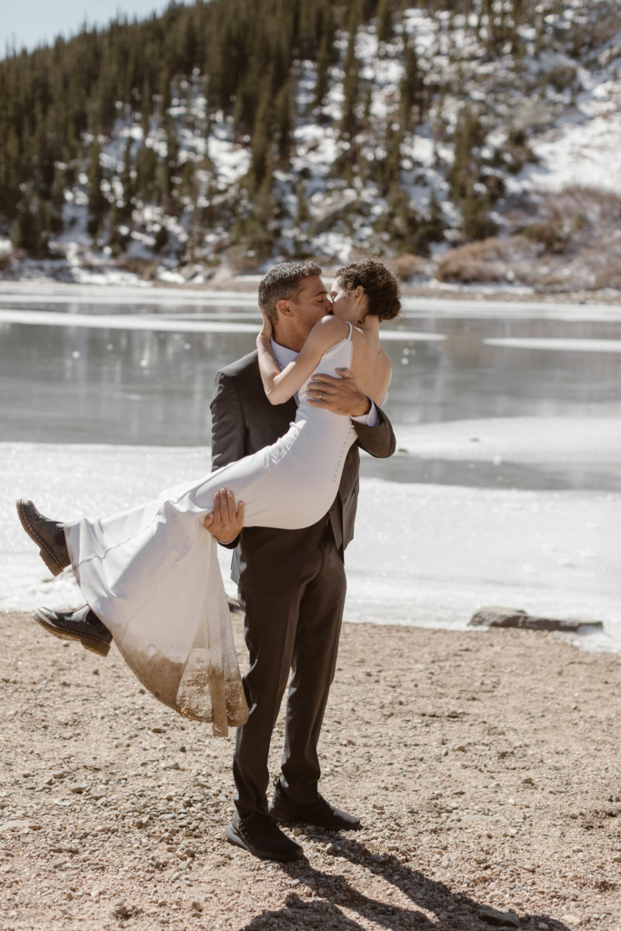 a couple wearing wedding attire hugging during their st marys glacier elopement