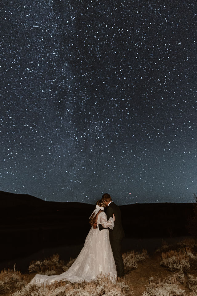 a couple wearing wedding clothes starring up at a start sky during their elopement