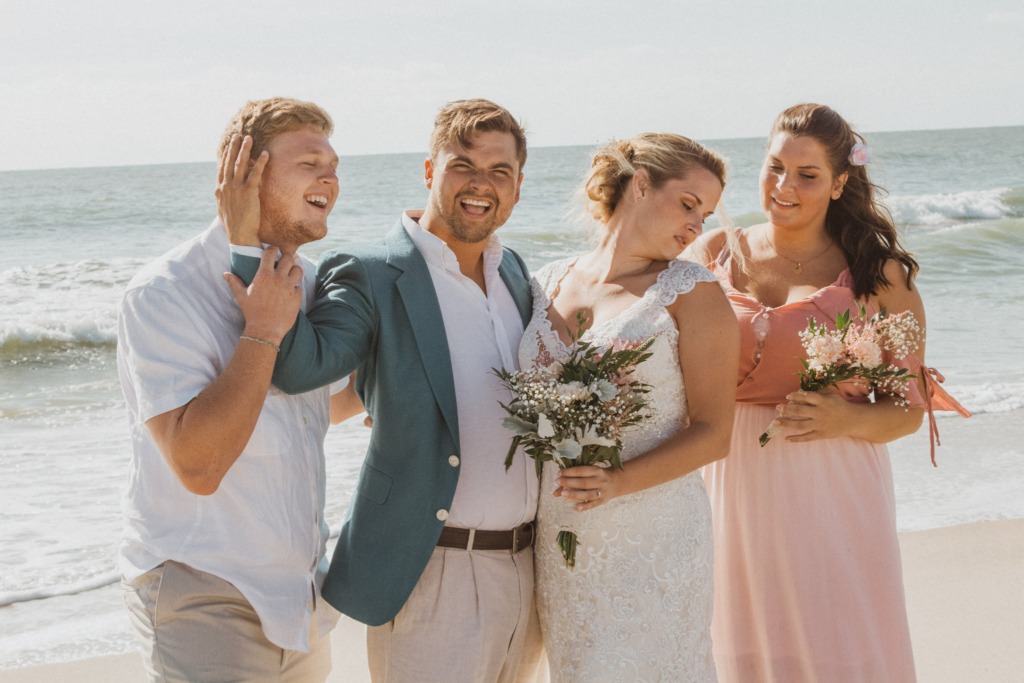 a bride and groom and their bridal party on the beach next to the ocean