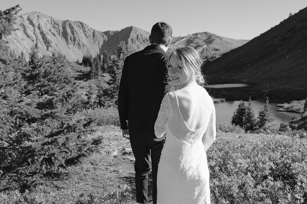a couple wearing wedding attire walking away from the camera during their loveland pass elopement