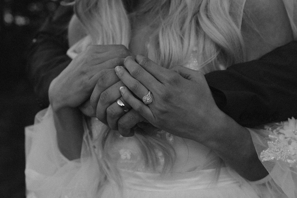 a black and white close up of a couple holding hands and their new wedding bands