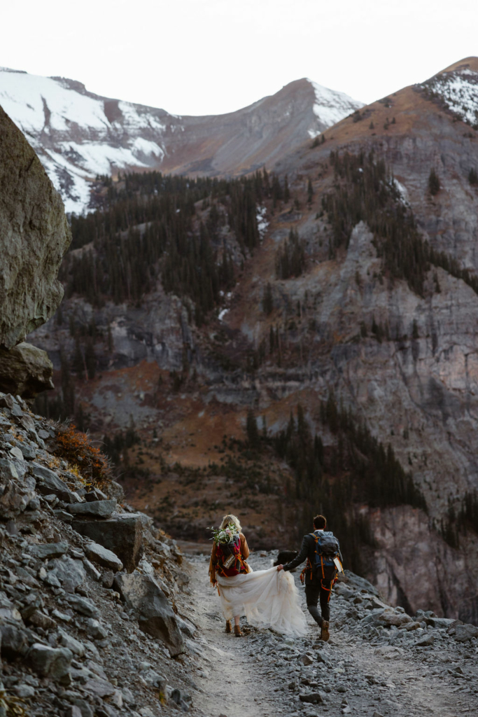 a couple wearing wedding attire kissing with big mountains in the background during their telluride hiking elopement
