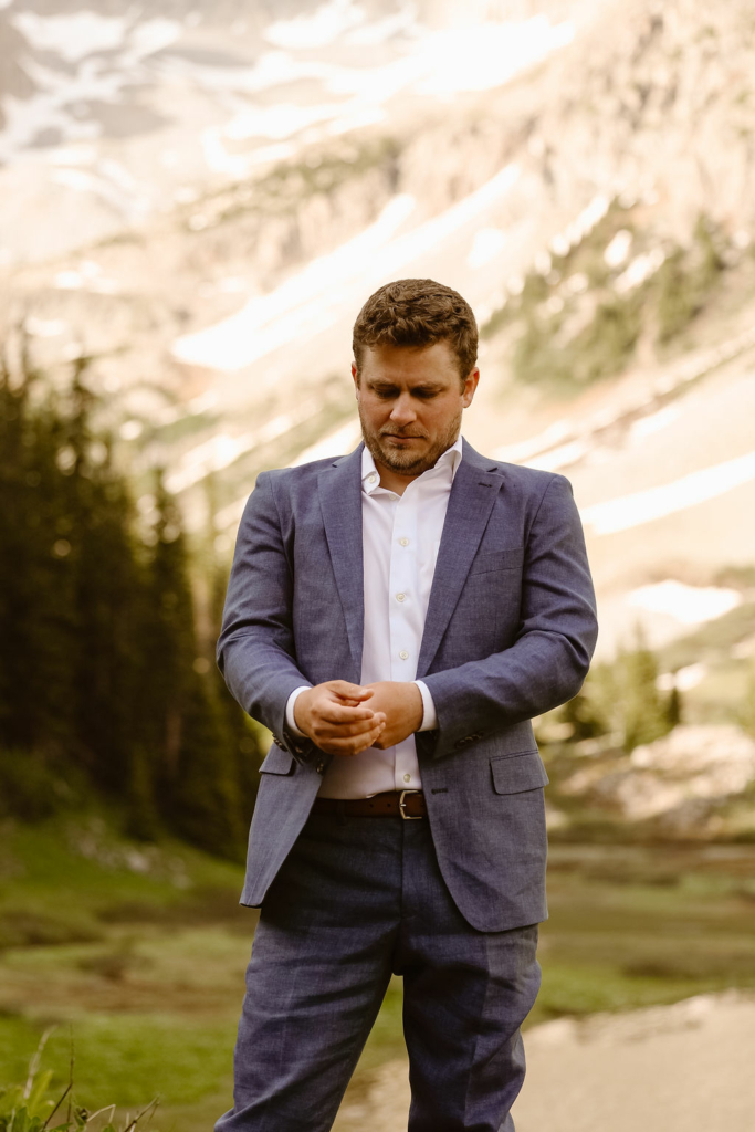 a groom wearing a traditional blue wedding suit in the mountains during his aspen elopement