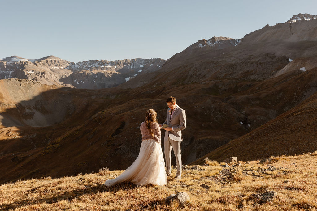 a couple standing on top of a mountain while wearing wedding clothes during their colorado elopement with a self solemnizing ceremony