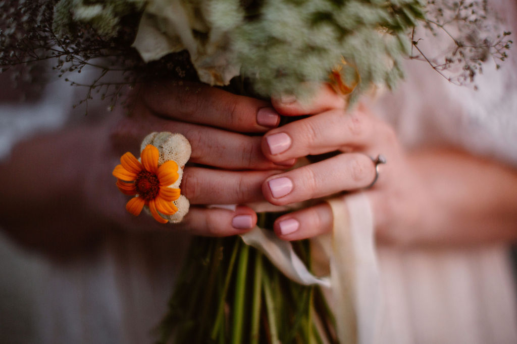 a close up of a bride holding a bouquet in her hands while wearing a floral ring